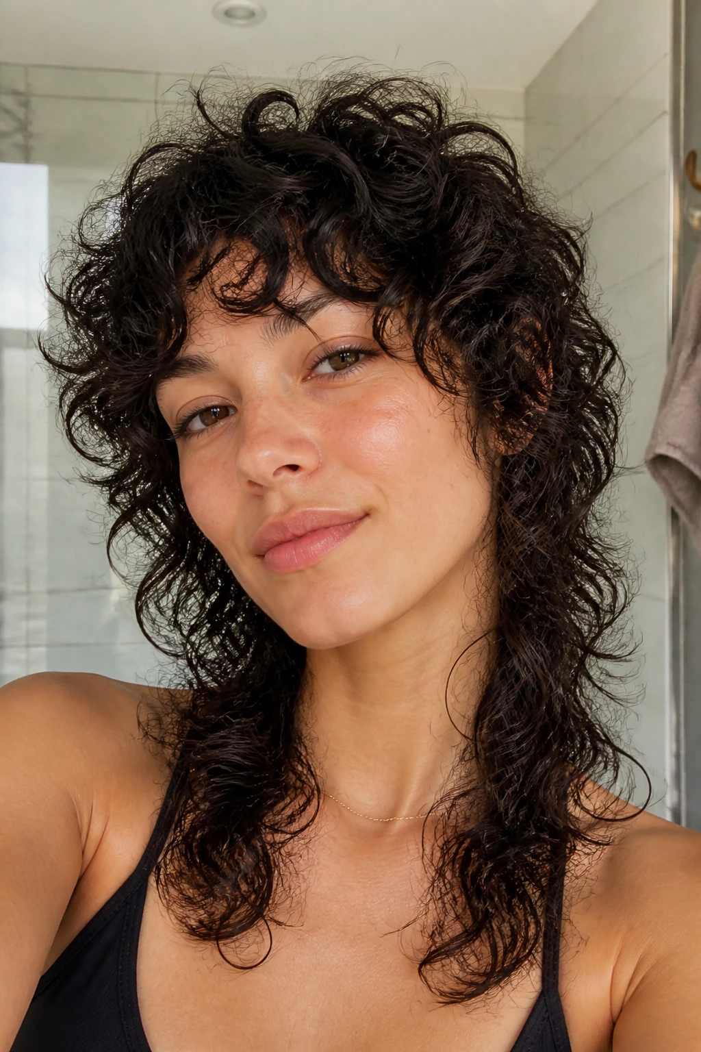 Close-up portrait of a real woman with a wash-and-go curly wolf cut showing natural texture and graceful growth