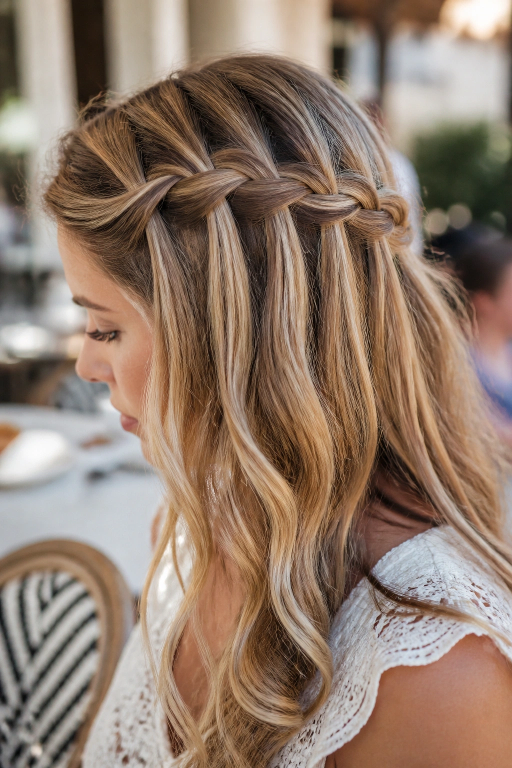 Side profile of a woman with a waterfall braid and cascading strands.