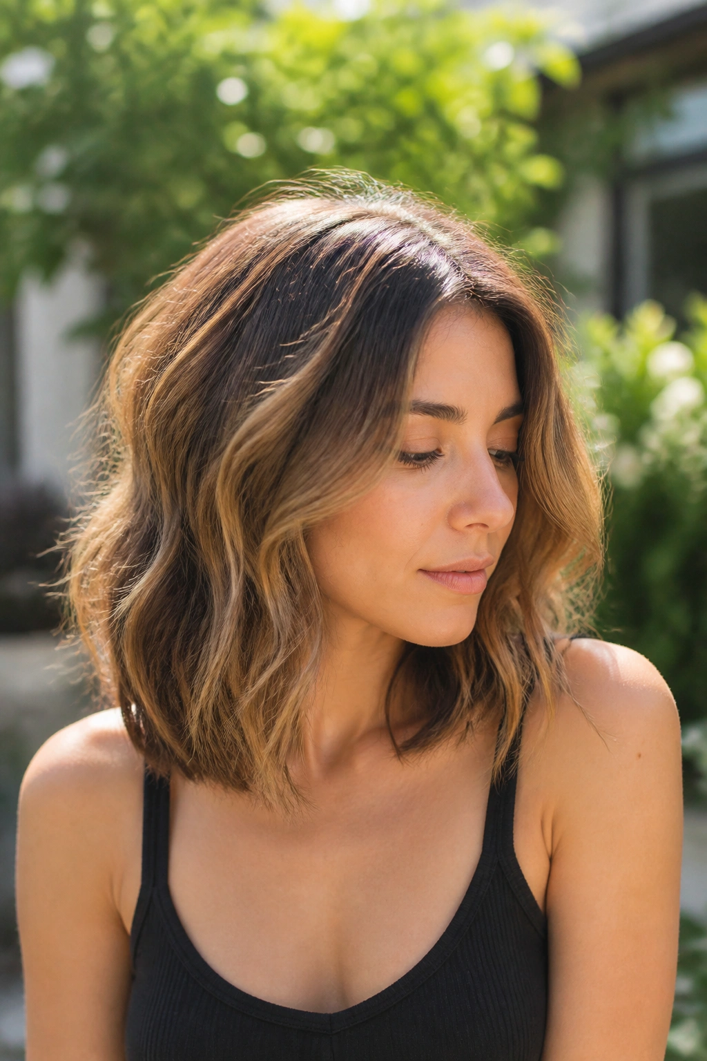 Medium close-up of a woman with a wavy lob and long layers outdoors.