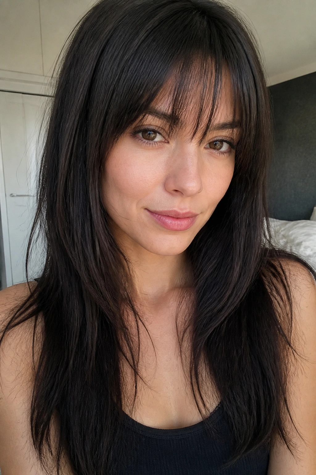 Portrait of a real woman with wispy brow-grazing bangs and light internal layers on straight hair