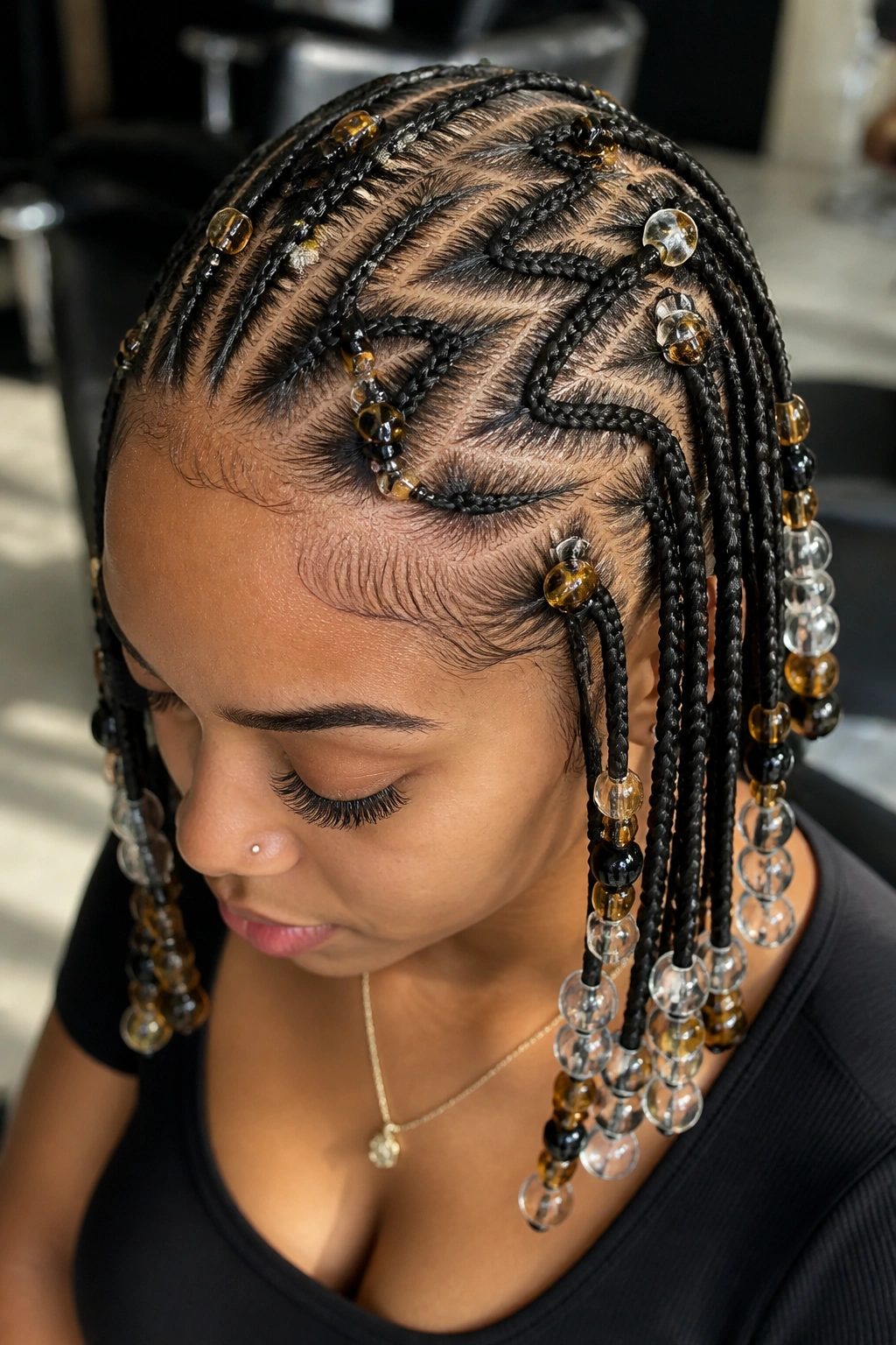 Close-up of zigzag-part cornrows with mixed bead sizes on a real woman